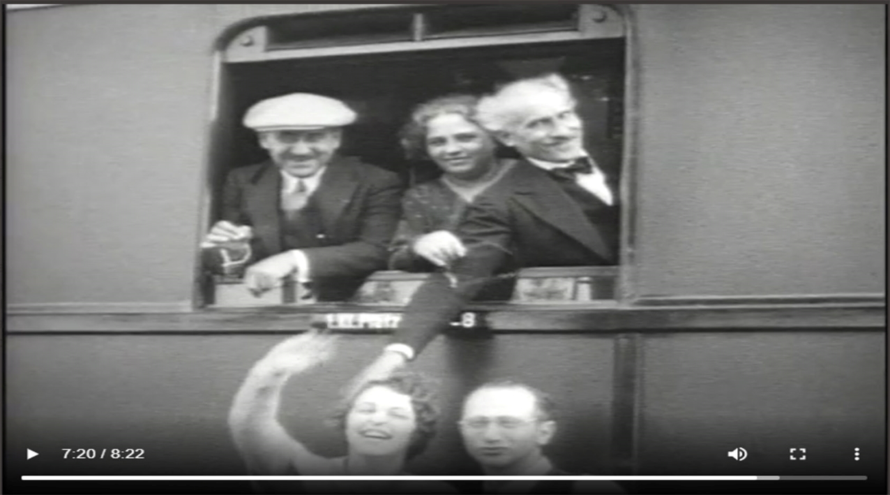 Toscanini, right, smirks and reaches out the window of a train to pat a woman's head. Other Philharmonic musicians and staff smile.