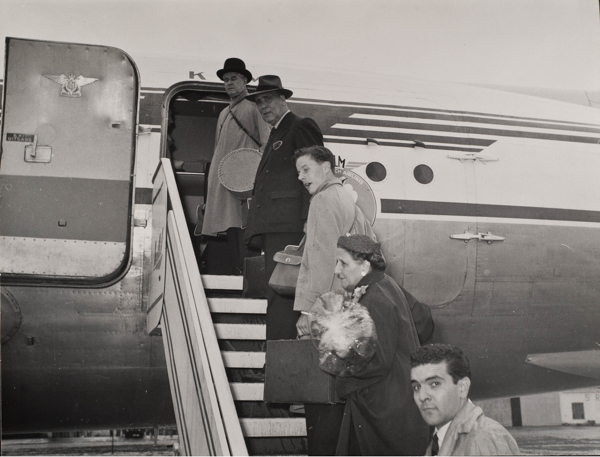 Historical black-and-white photograph of travelers descending from an airplane